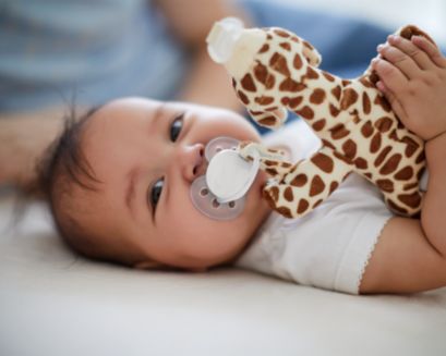 Baby smiling while holding a snuggle